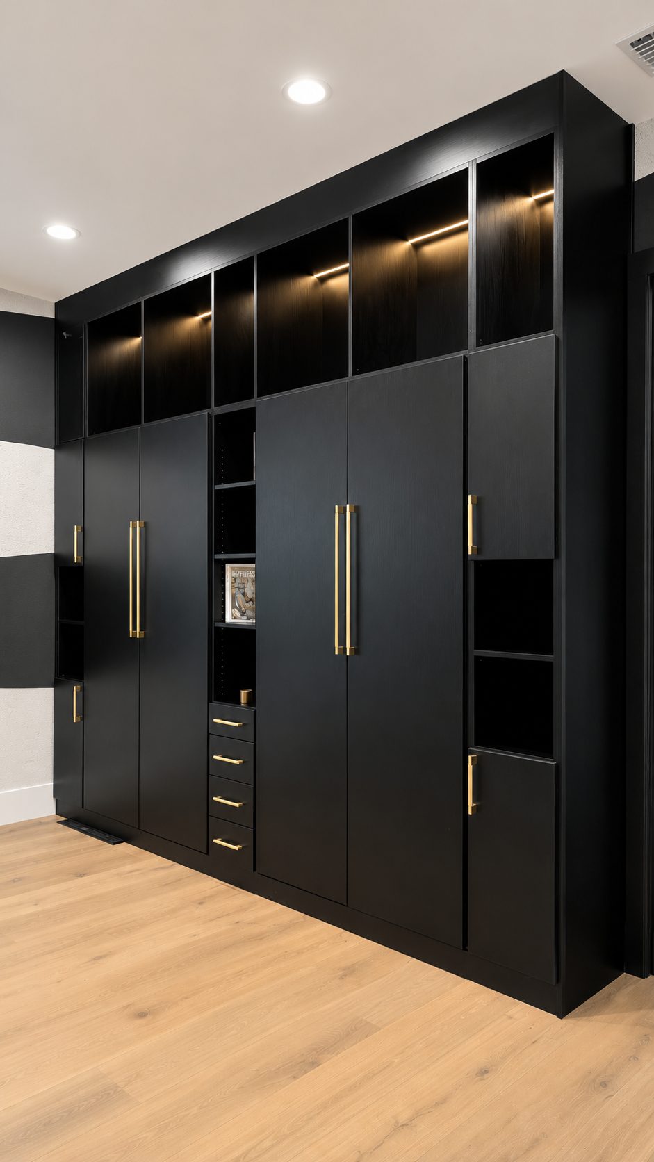 Matte black built-in wardrobe with brass handles and LED upper cabinets