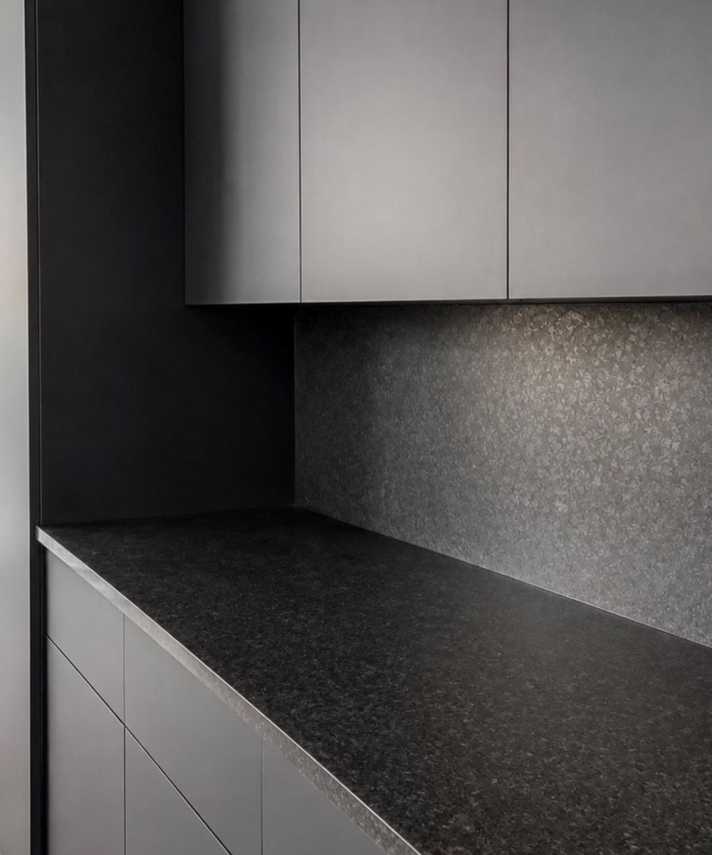 Dark custom kitchen cabinetry with a speckled stone countertop