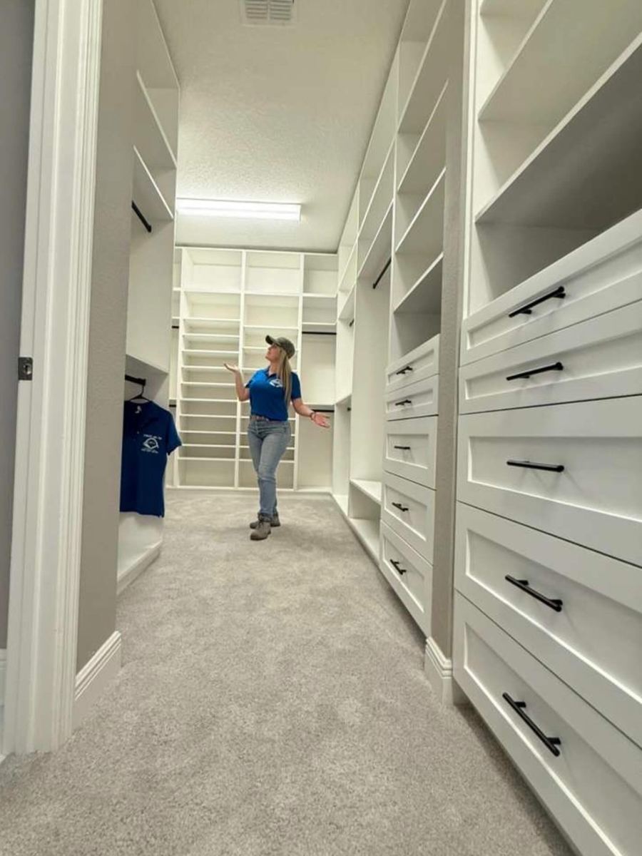 Long white walk-in closet with drawer banks down both walls