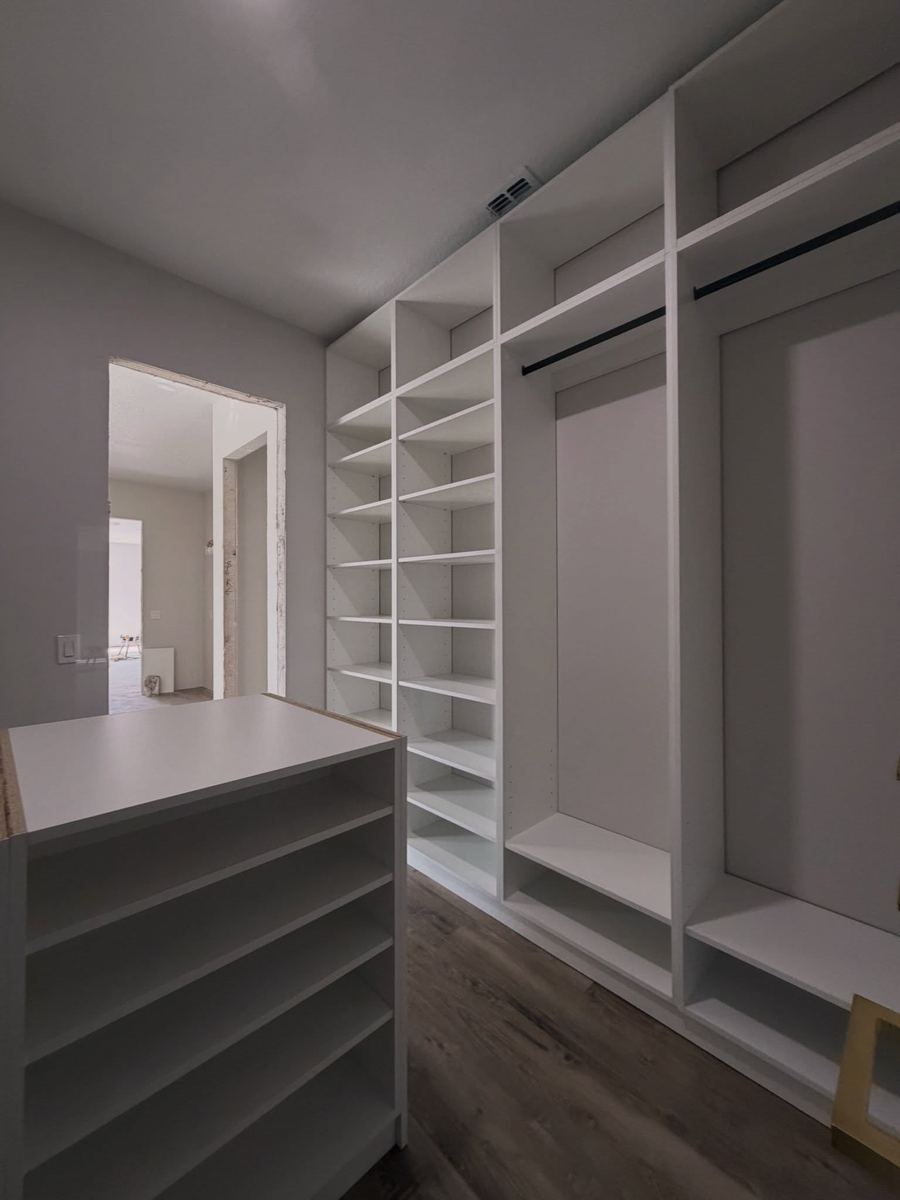 Newly finished white walk-in closet with a drawer island