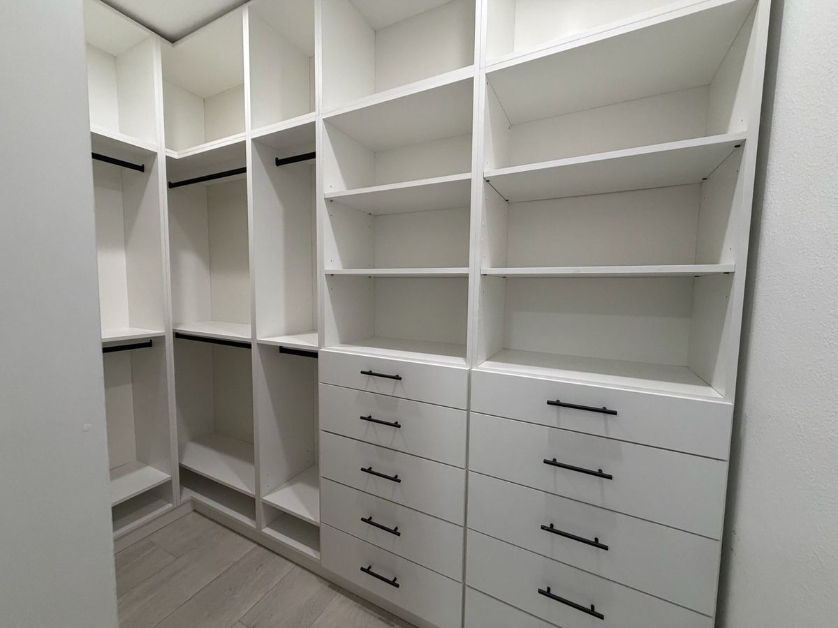 White walk-in closet with adjustable shelving and deep drawers
