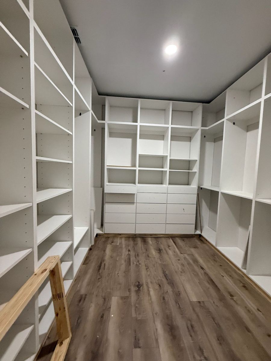 White walk-in closet with a full height shoe wall