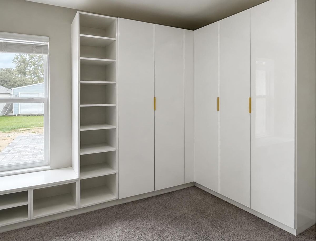 Bright white walk-in closet with brass pulls and a window seat