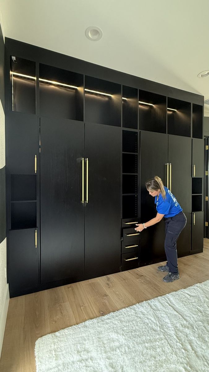 Full wall black wardrobe with brass handles and integrated lighting