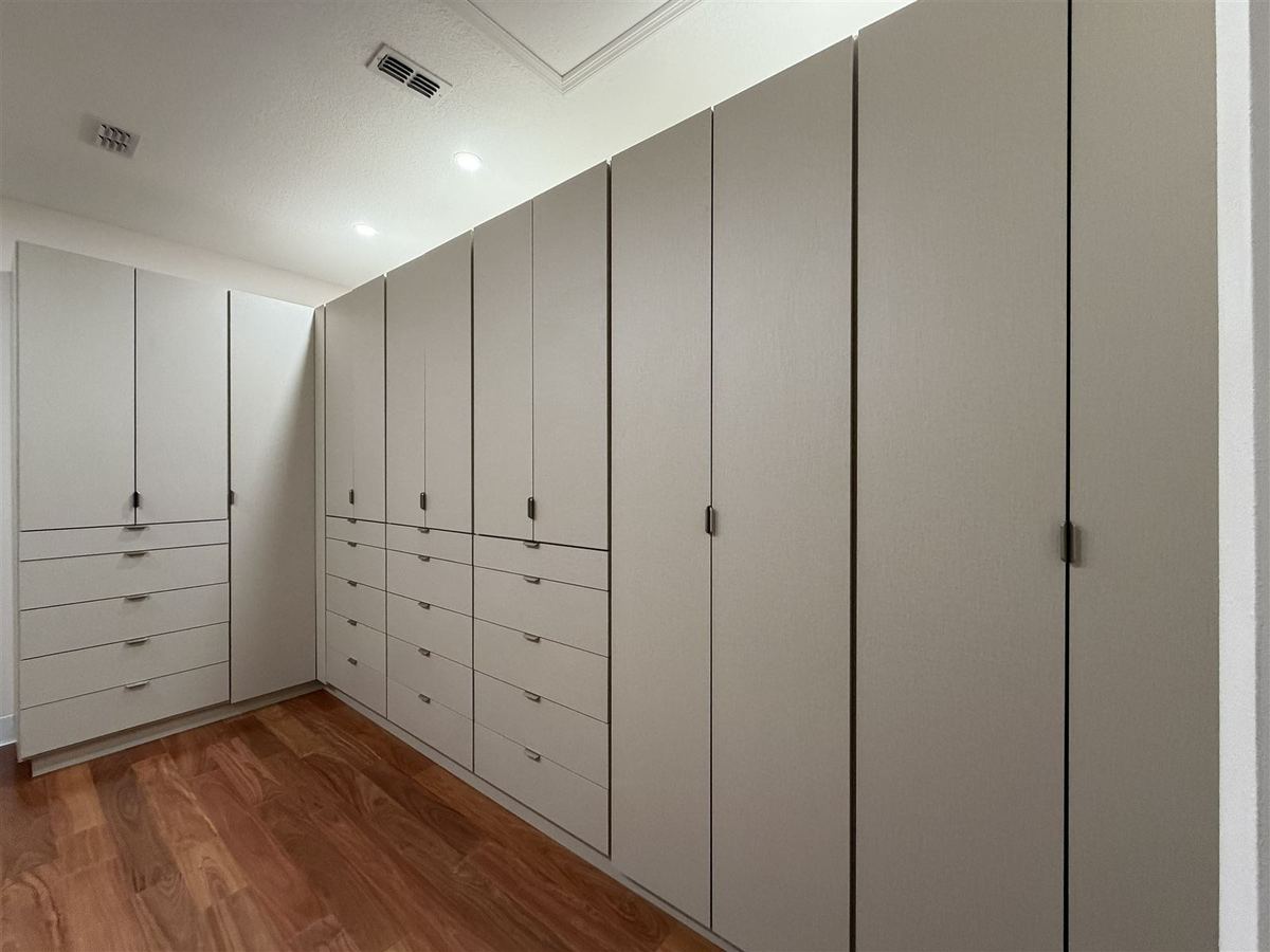 Wall to wall greige wardrobe with drawers and tall doors